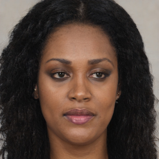 Joyful black young-adult female with long  black hair and brown eyes