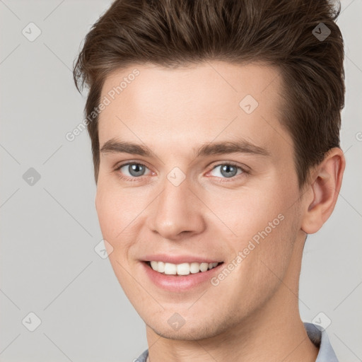 Joyful white young-adult male with short  brown hair and grey eyes