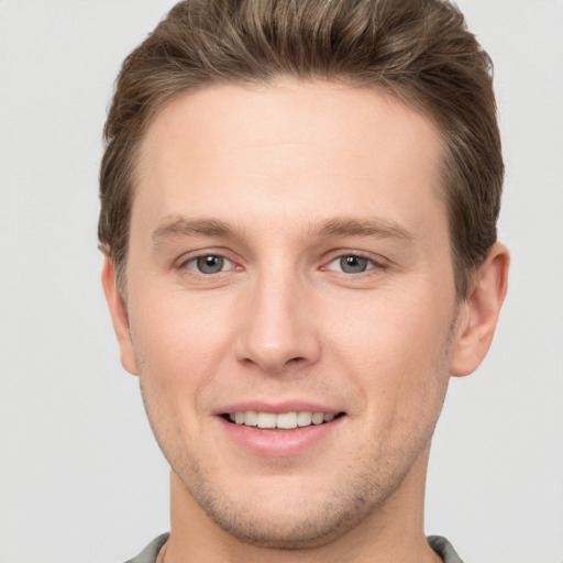 Joyful white young-adult male with short  brown hair and grey eyes