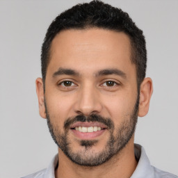 Joyful latino young-adult male with short  black hair and brown eyes