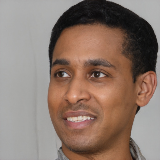 Joyful black young-adult male with short  black hair and brown eyes