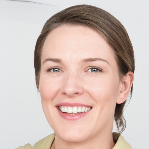 Joyful white young-adult female with medium  brown hair and grey eyes