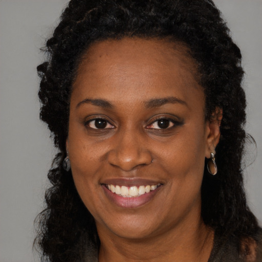 Joyful black young-adult female with long  brown hair and brown eyes