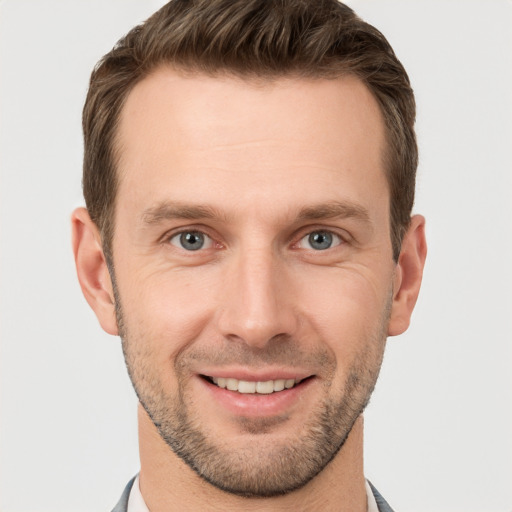 Joyful white young-adult male with short  brown hair and grey eyes