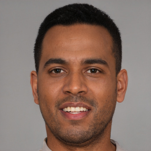 Joyful black young-adult male with short  brown hair and brown eyes