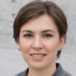 Joyful white young-adult female with medium  brown hair and grey eyes