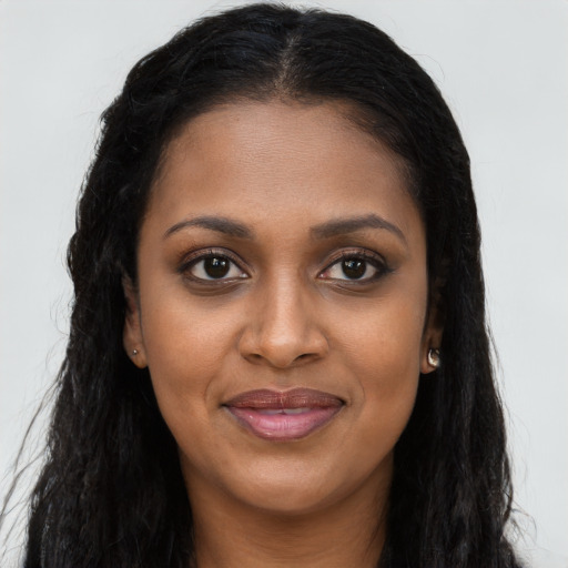 Joyful black young-adult female with long  brown hair and brown eyes
