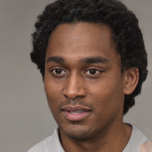 Joyful black young-adult male with short  black hair and brown eyes