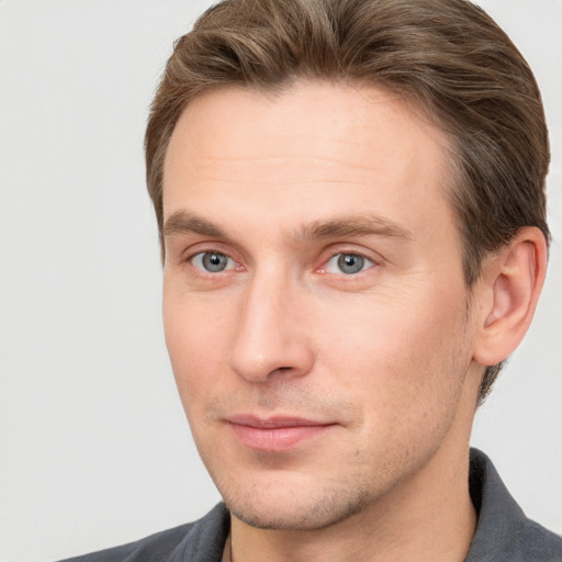 Joyful white young-adult male with short  brown hair and grey eyes