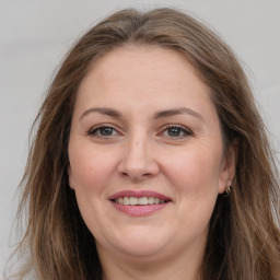 Joyful white adult female with long  brown hair and grey eyes