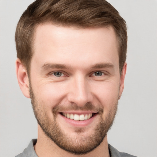 Joyful white young-adult male with short  brown hair and grey eyes