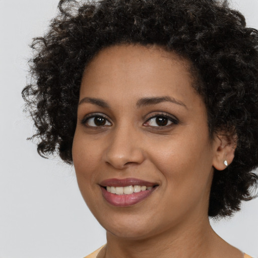Joyful black young-adult female with long  brown hair and brown eyes
