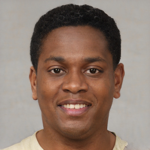 Joyful black young-adult male with short  brown hair and brown eyes