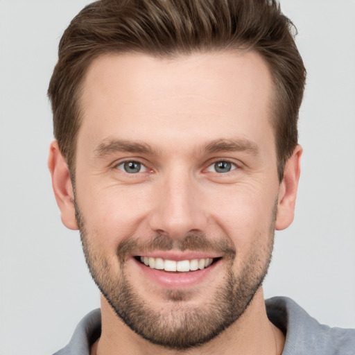 Joyful white young-adult male with short  brown hair and grey eyes