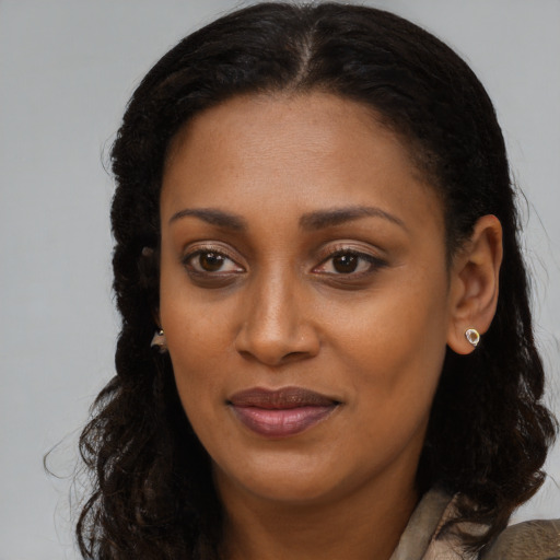 Joyful black young-adult female with long  brown hair and brown eyes