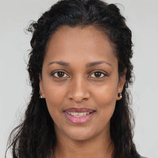Joyful black young-adult female with long  brown hair and brown eyes
