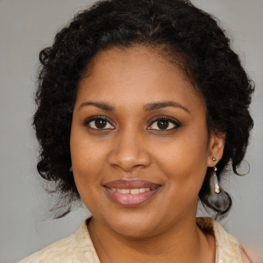 Joyful black young-adult female with long  brown hair and brown eyes