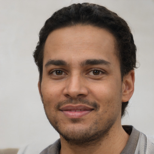 Joyful latino young-adult male with short  black hair and brown eyes