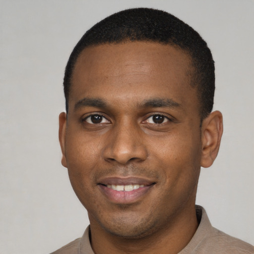 Joyful black young-adult male with short  brown hair and brown eyes
