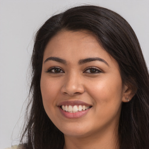 Joyful latino young-adult female with long  brown hair and brown eyes