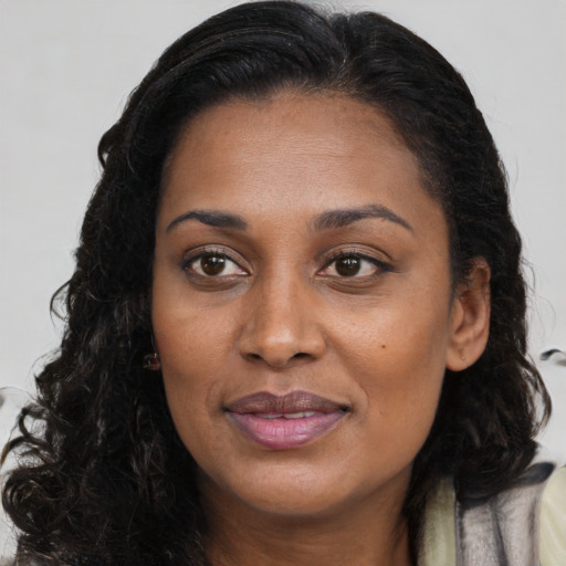 Joyful black young-adult female with long  brown hair and brown eyes
