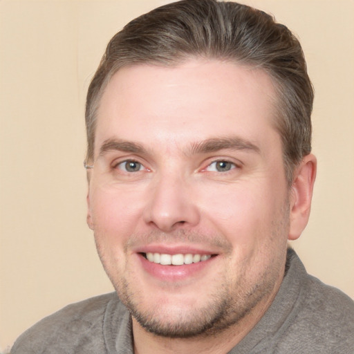 Joyful white young-adult male with short  brown hair and grey eyes