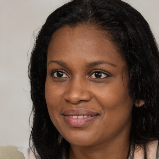 Joyful black young-adult female with long  brown hair and brown eyes