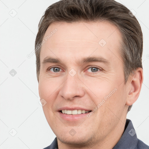 Joyful white young-adult male with short  brown hair and grey eyes