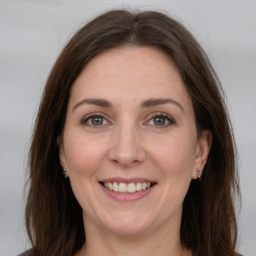 Joyful white adult female with long  brown hair and grey eyes