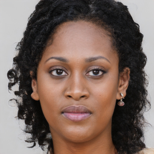 Joyful black young-adult female with long  brown hair and brown eyes