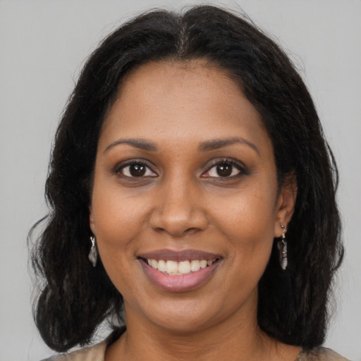 Joyful black young-adult female with long  brown hair and brown eyes