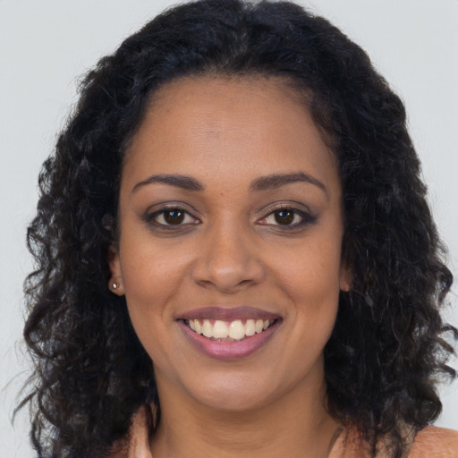 Joyful black young-adult female with long  brown hair and brown eyes