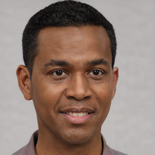 Joyful black young-adult male with short  black hair and brown eyes