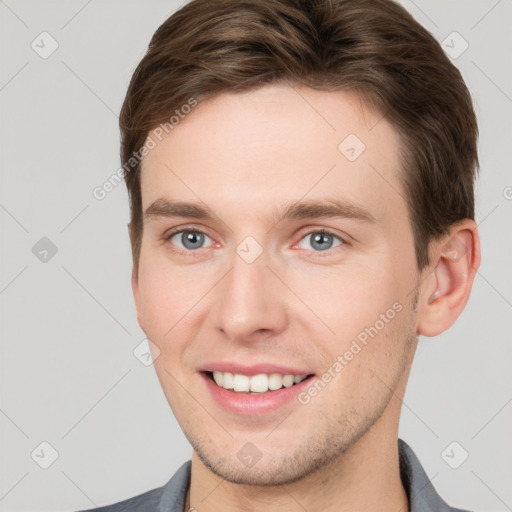 Joyful white young-adult male with short  brown hair and grey eyes