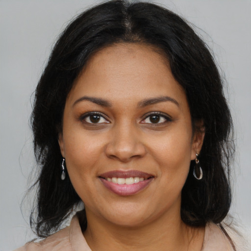 Joyful black young-adult female with long  brown hair and brown eyes