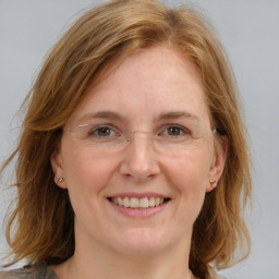 Joyful white adult female with medium  brown hair and blue eyes