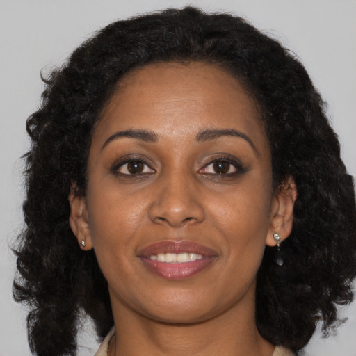 Joyful black young-adult female with long  brown hair and brown eyes