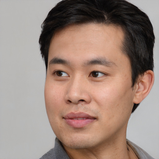 Joyful asian young-adult male with short  brown hair and brown eyes