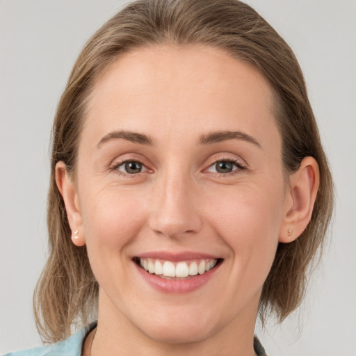 Joyful white young-adult female with medium  brown hair and grey eyes