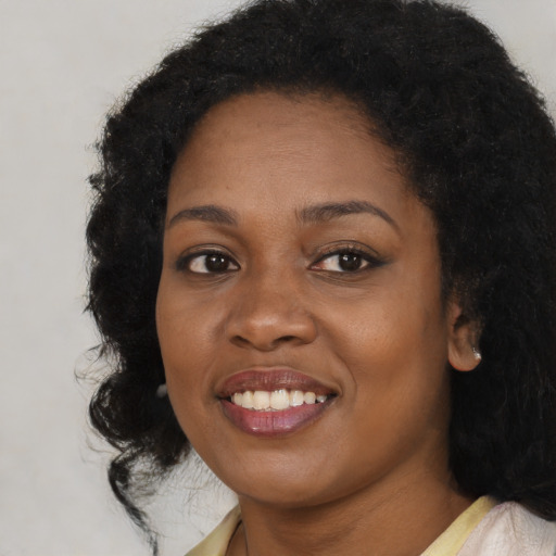 Joyful black young-adult female with long  black hair and brown eyes