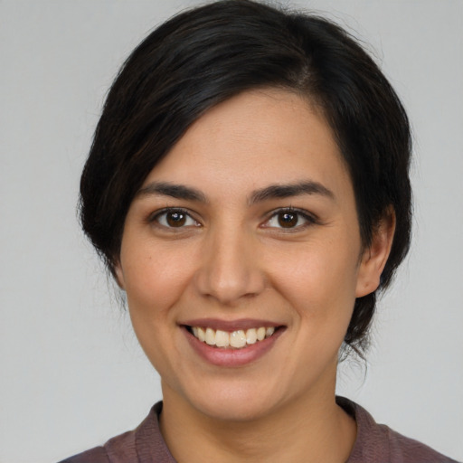 Joyful latino young-adult female with medium  brown hair and brown eyes