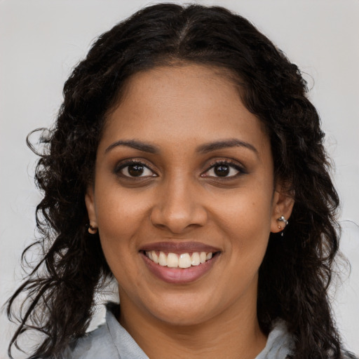 Joyful black young-adult female with long  brown hair and brown eyes