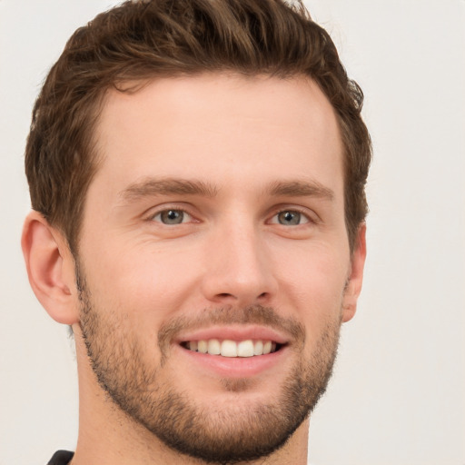 Joyful white young-adult male with short  brown hair and grey eyes