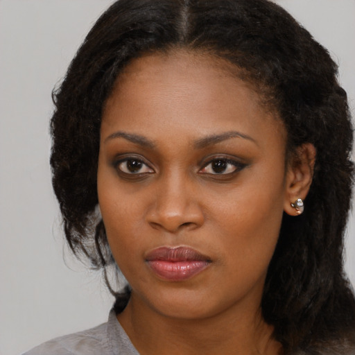 Joyful black young-adult female with long  brown hair and brown eyes