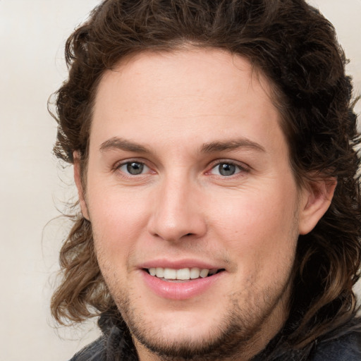 Joyful white young-adult male with long  brown hair and brown eyes