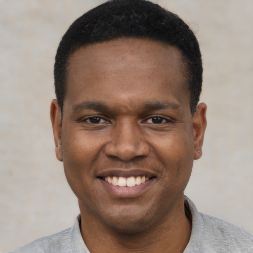 Joyful black young-adult male with short  black hair and brown eyes