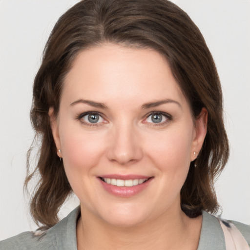 Joyful white young-adult female with medium  brown hair and grey eyes