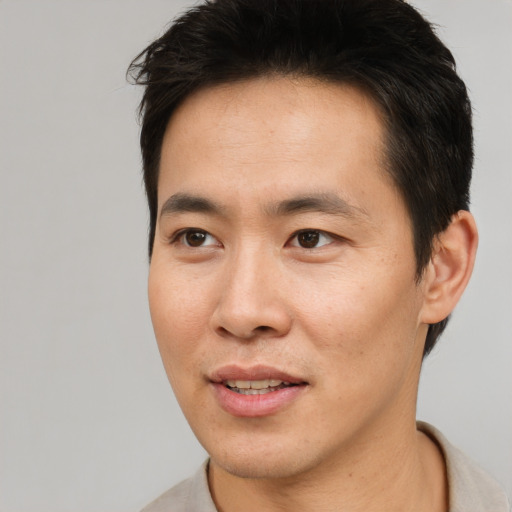 Joyful asian young-adult male with short  brown hair and brown eyes