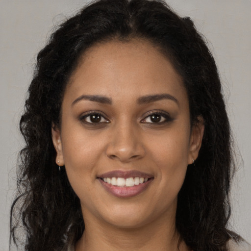 Joyful black young-adult female with long  brown hair and brown eyes