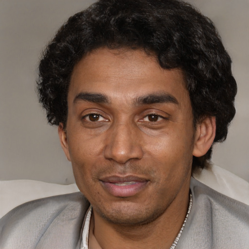 Joyful black adult male with short  black hair and brown eyes